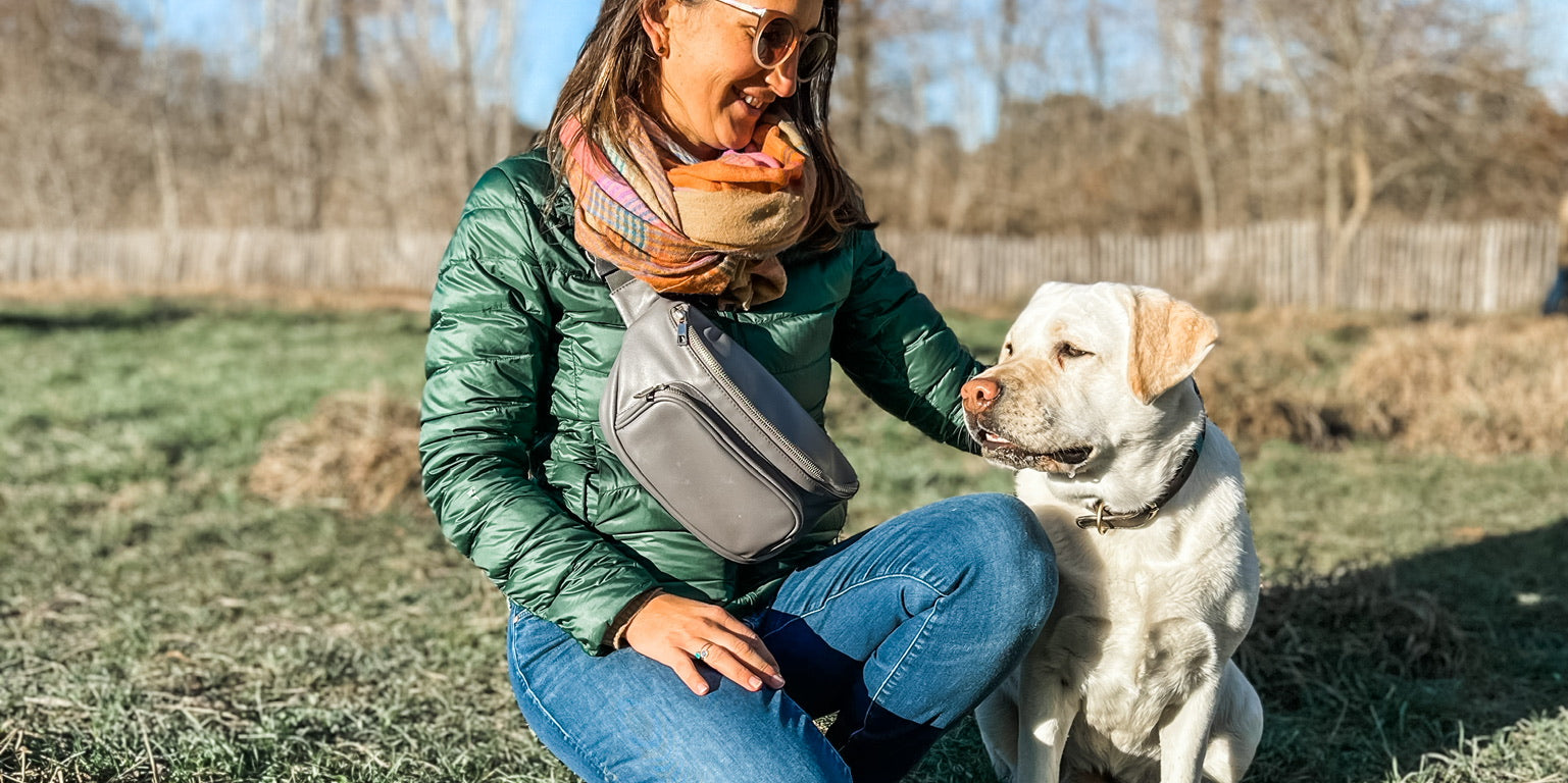 Woman wearing dog walking bag fanny pack playing with dogs