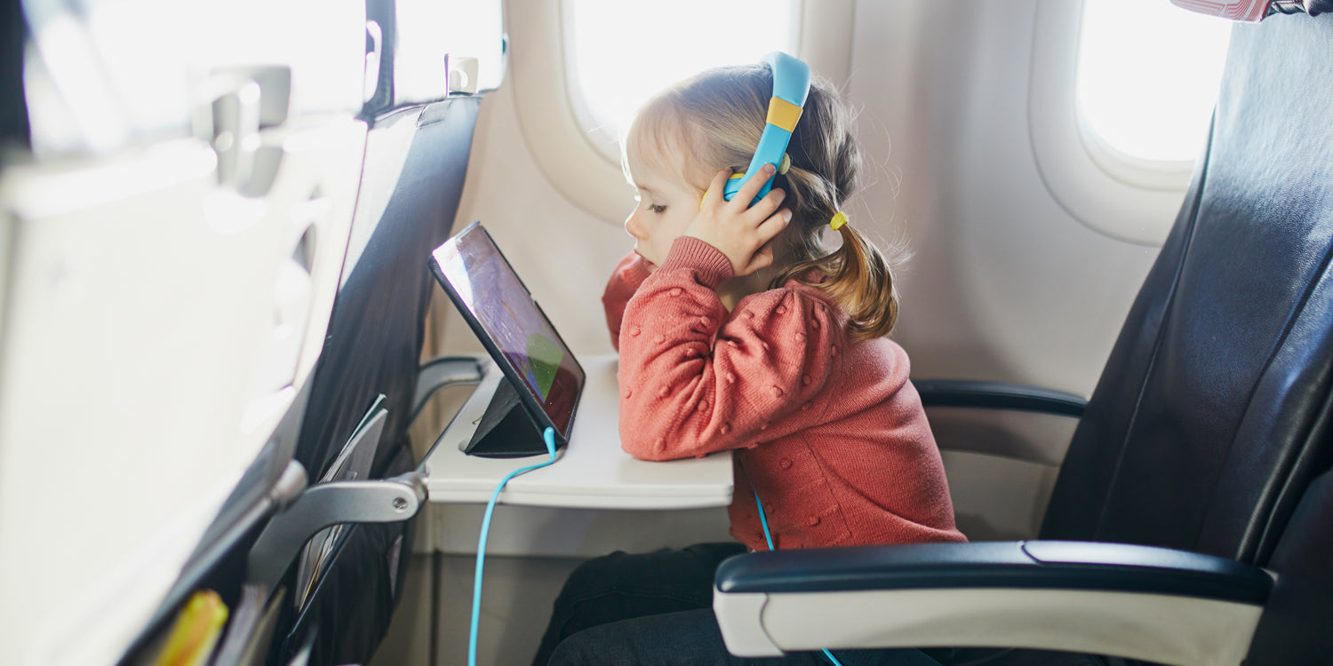 toddler girl watching ipad on plane while listening with her headphones