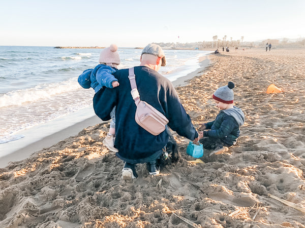 Dad wearing Kibou dad diaper bag in blush with kids on beach